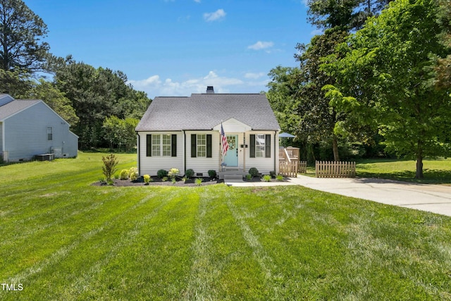 cape cod-style house featuring an outbuilding, central AC unit, fence, a storage unit, and a front lawn