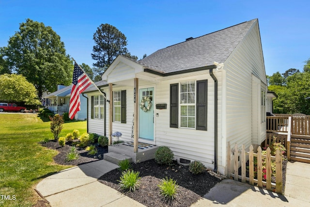 bungalow-style house with a front yard, fence, and roof with shingles