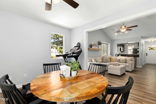 dining room with a ceiling fan, vaulted ceiling, plenty of natural light, and light wood finished floors