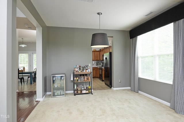 interior space featuring light colored carpet, baseboards, visible vents, and wine cooler