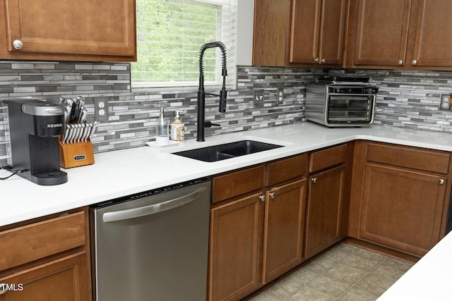 kitchen with tasteful backsplash, dishwasher, a sink, light countertops, and a toaster