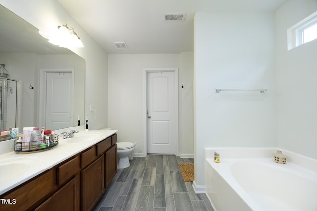 bathroom featuring a sink, double vanity, wood finished floors, visible vents, and a garden tub