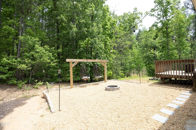 view of play area featuring a pergola, an outdoor fire pit, and a deck