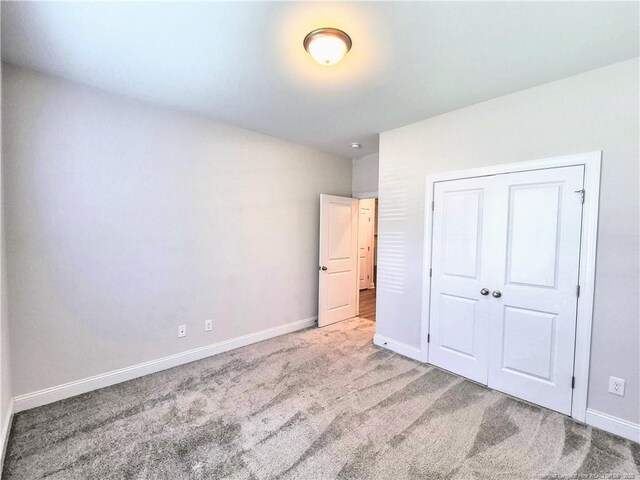 unfurnished bedroom with carpet flooring, baseboards, and a closet