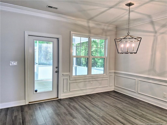 unfurnished dining area featuring crown molding, a notable chandelier, a wainscoted wall, visible vents, and dark wood-style floors