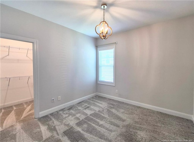 spare room featuring baseboards, carpet, and a chandelier