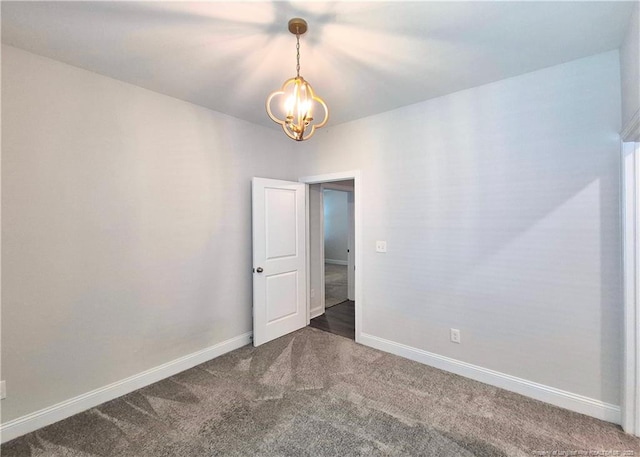 empty room with baseboards, a chandelier, and dark carpet
