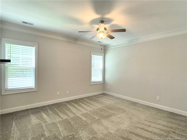 carpeted empty room featuring visible vents, ornamental molding, baseboards, and ceiling fan