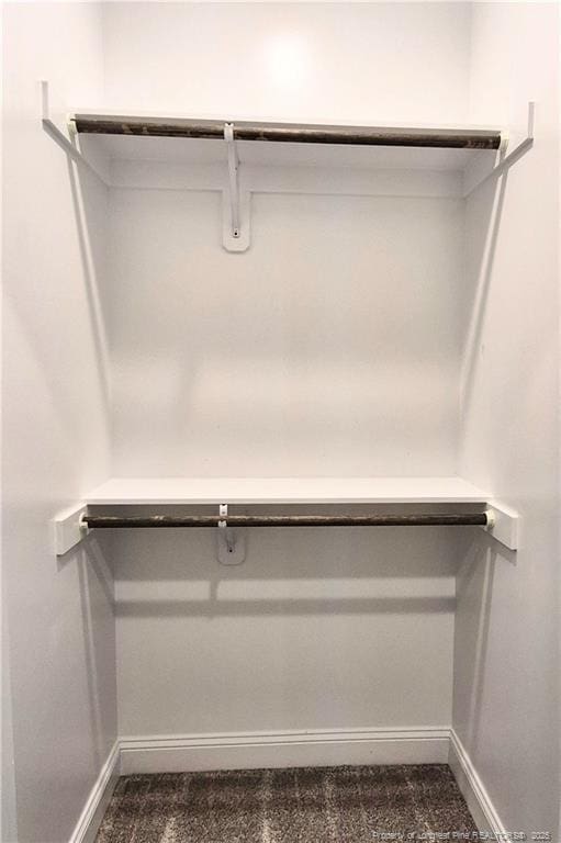 walk in closet featuring dark carpet