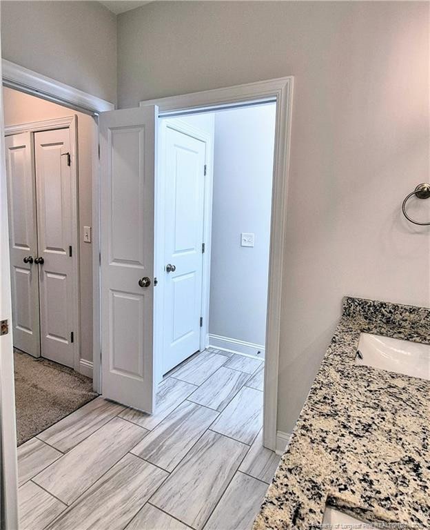 bathroom with a sink, baseboards, and wood finish floors