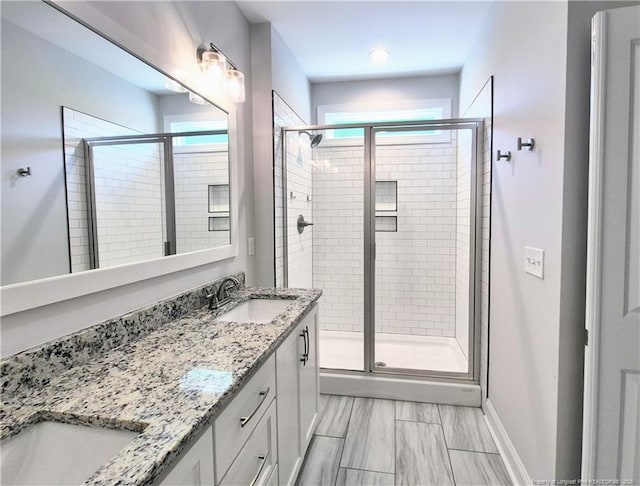 bathroom featuring a sink, a shower stall, and double vanity
