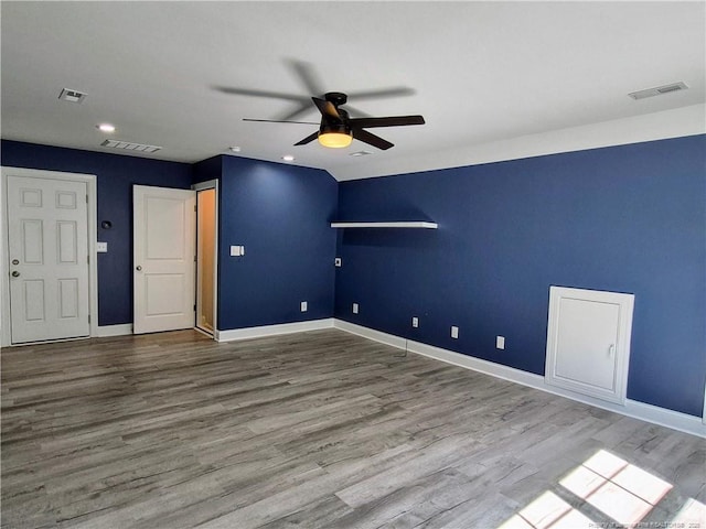 spare room with baseboards, ceiling fan, wood finished floors, and visible vents