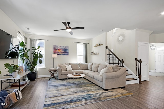 living area with a ceiling fan, baseboards, dark wood-type flooring, visible vents, and stairway