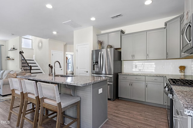kitchen featuring a sink, appliances with stainless steel finishes, decorative backsplash, and gray cabinetry