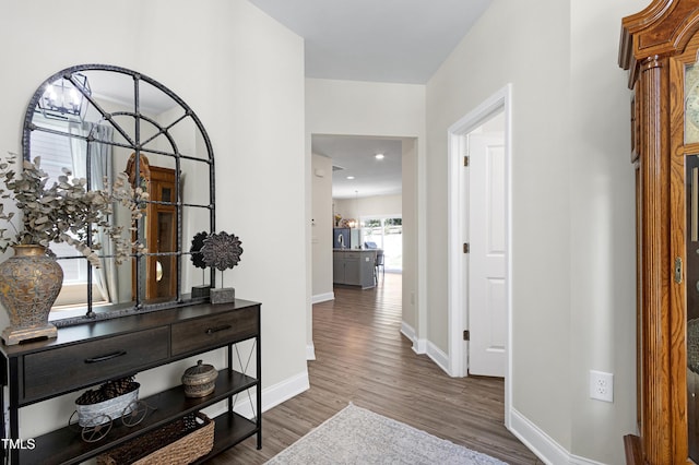 hall featuring baseboards, recessed lighting, and wood finished floors