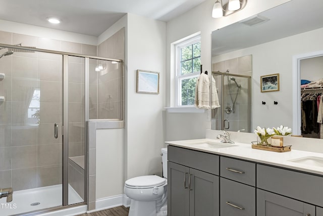 bathroom with double vanity, visible vents, a stall shower, a sink, and toilet