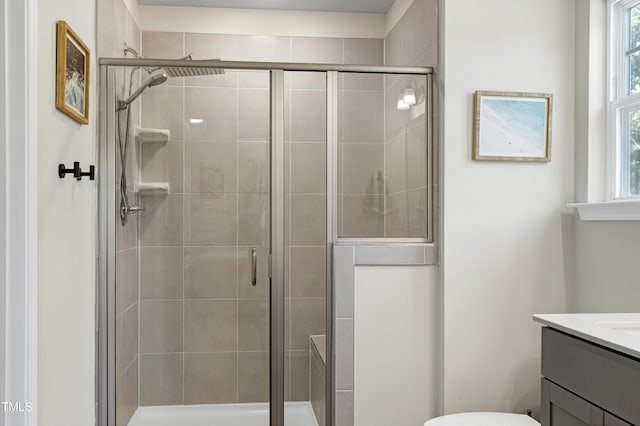 bathroom with vanity, a shower stall, and toilet
