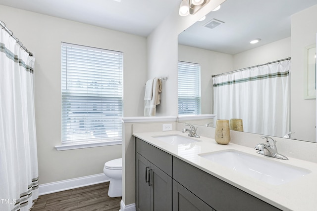 full bathroom with a sink, toilet, wood finished floors, and visible vents
