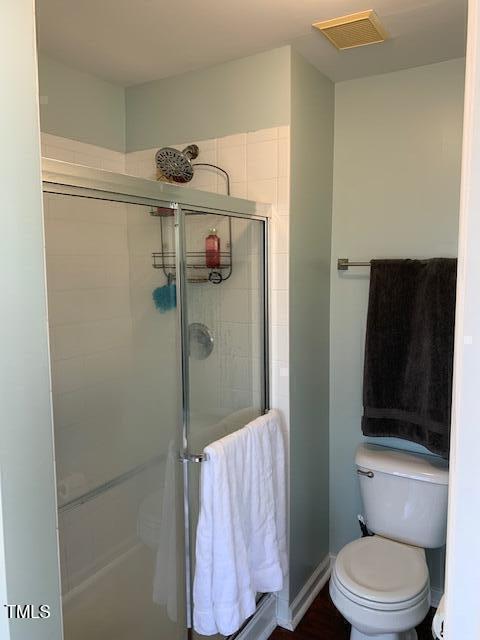 bathroom featuring toilet, visible vents, and a stall shower