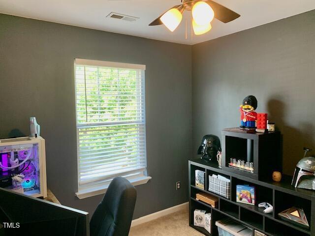 carpeted office space with visible vents, a ceiling fan, and baseboards