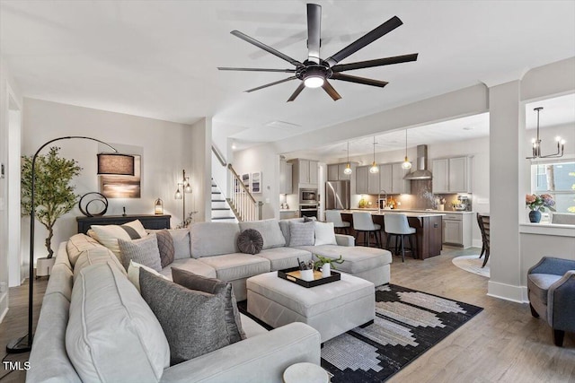 7729 Calcutta Dr, Willow Springs, NC 27592 - living room with stairs, baseboards, light wood-style flooring, and ceiling fan with notable chandelier