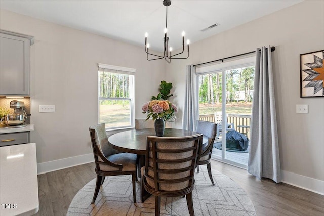 7729 Calcutta Dr, Willow Springs, NC 27592 - dining space with visible vents, wood finished floors, a chandelier, and a healthy amount of sunlight