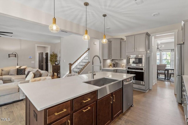 7729 Calcutta Dr, Willow Springs, NC 27592 - kitchen with a sink, light countertops, stainless steel appliances, open floor plan, and light wood-type flooring