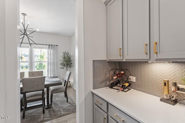 7729 Calcutta Dr, Willow Springs, NC 27592 - bar featuring baseboards, decorative backsplash, wood finished floors, and a notable chandelier