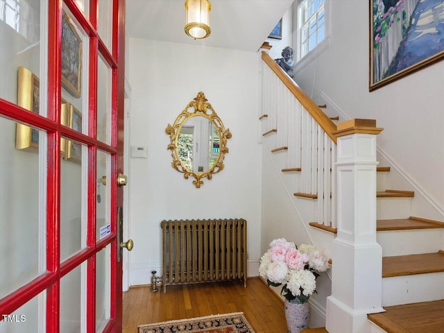 entryway featuring radiator heating unit, stairway, and wood finished floors