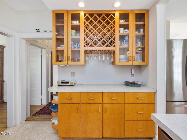 kitchen featuring light countertops, glass insert cabinets, and freestanding refrigerator
