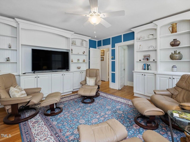 living room featuring light wood finished floors, ceiling fan, and built in shelves