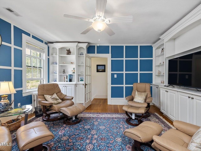 living room featuring ceiling fan, visible vents, and wood finished floors