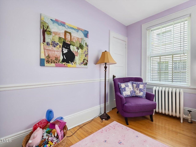 living area featuring baseboards, radiator, and wood finished floors