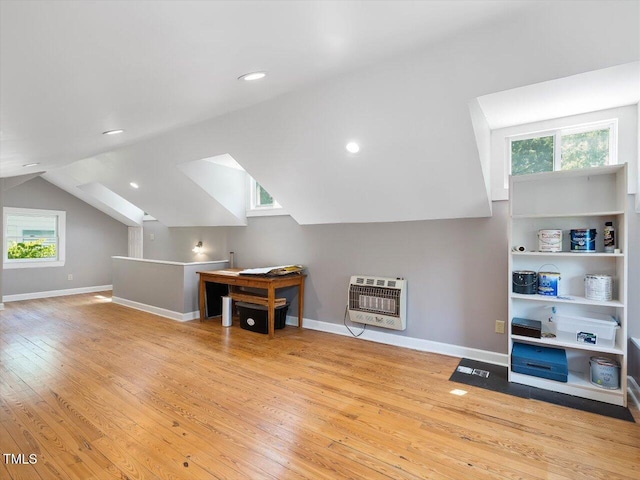 additional living space with baseboards, heating unit, plenty of natural light, and hardwood / wood-style flooring
