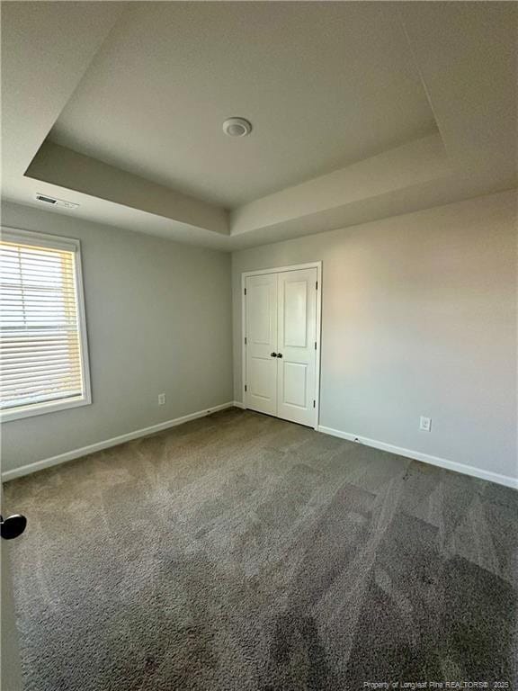 331 Brentmoor Dr, Raeford, NC 28376 - unfurnished bedroom featuring a tray ceiling, visible vents, baseboards, and dark colored carpet
