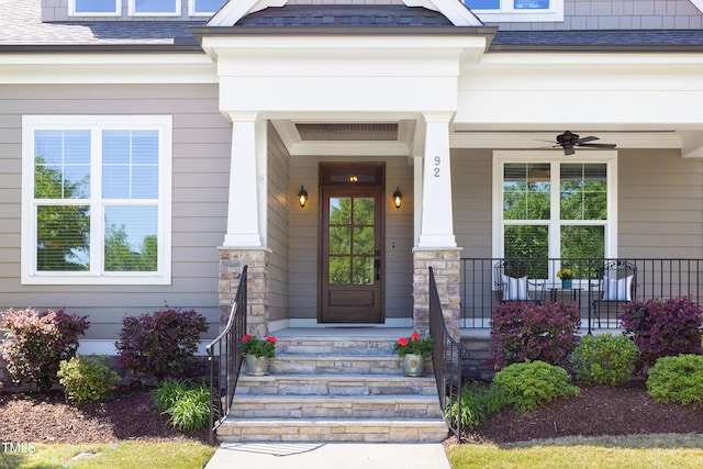entrance to property with a porch, ceiling fan, and roof with shingles