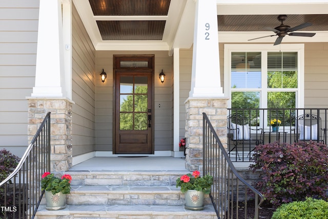 doorway to property with ceiling fan, covered porch, and stone siding