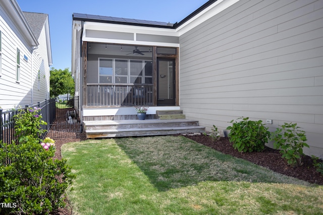 property entrance with a lawn, a ceiling fan, and fence