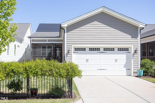 view of front of home featuring concrete driveway, solar panels, a sunroom, and a garage