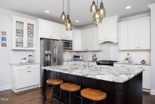 kitchen featuring a kitchen breakfast bar, dark wood finished floors, a sink, white cabinets, and stainless steel appliances