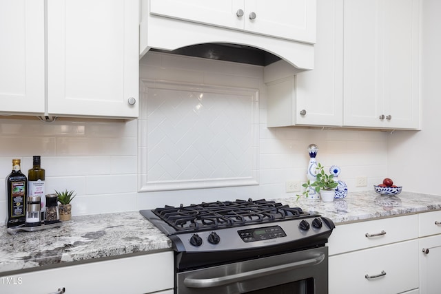 kitchen featuring stainless steel range with gas stovetop, white cabinets, light stone countertops, and backsplash