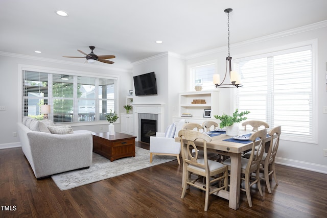 dining area with a glass covered fireplace, baseboards, crown molding, and dark wood-type flooring
