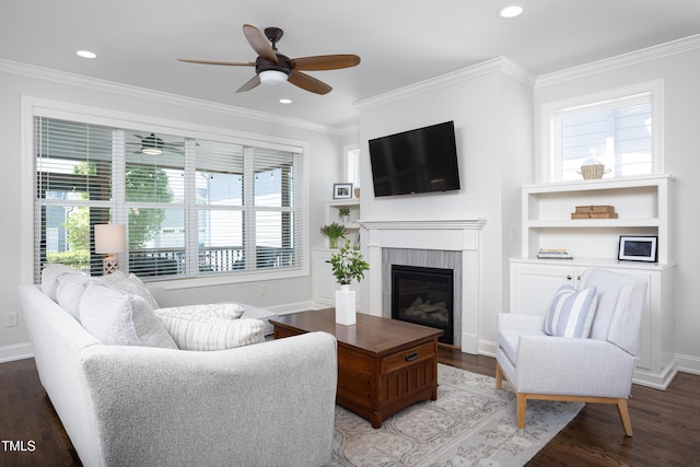 living area featuring a ceiling fan, wood finished floors, a glass covered fireplace, ornamental molding, and recessed lighting