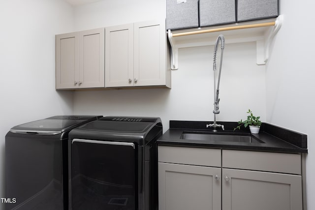 clothes washing area with cabinet space, separate washer and dryer, and a sink