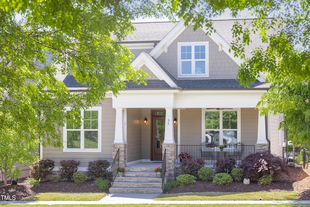 craftsman inspired home featuring covered porch and a shingled roof