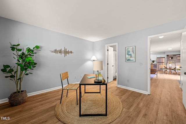 office space with baseboards and light wood-style flooring