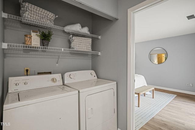 laundry area featuring independent washer and dryer, laundry area, baseboards, and wood finished floors