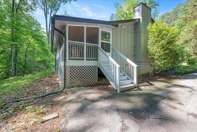 rear view of house with a sunroom and a chimney