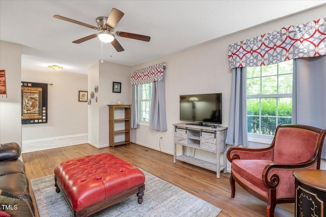 living area with ceiling fan, baseboards, and wood finished floors