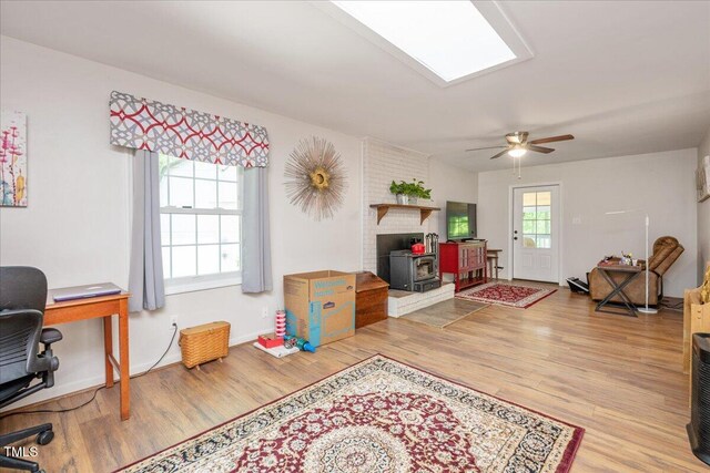 playroom with a wood stove, baseboards, ceiling fan, and wood finished floors